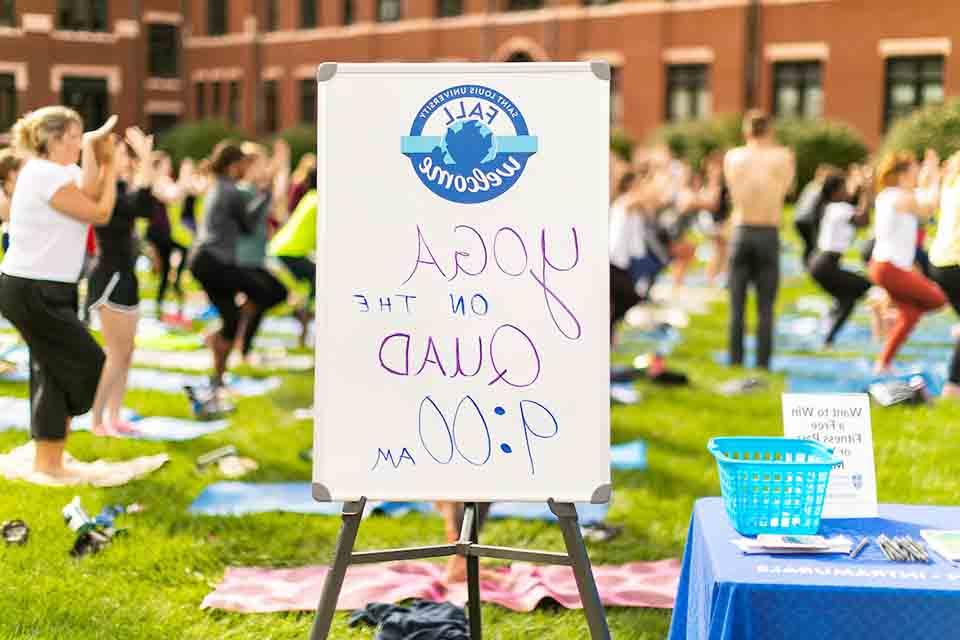 People practicing yoga in background with sign reading "方庭上的瑜伽, 9 a.m.在前景中.